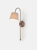 Arched wall light made from brass tubing and walnut accents with circular back plate and linen shade - Light on.