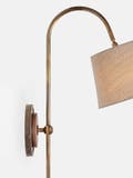 Arched wall light made from brass tubing and walnut accents with circular back plate and linen shade.