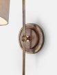 Circular wall light back plate made from solid walnut with sand-cast brass casing.
