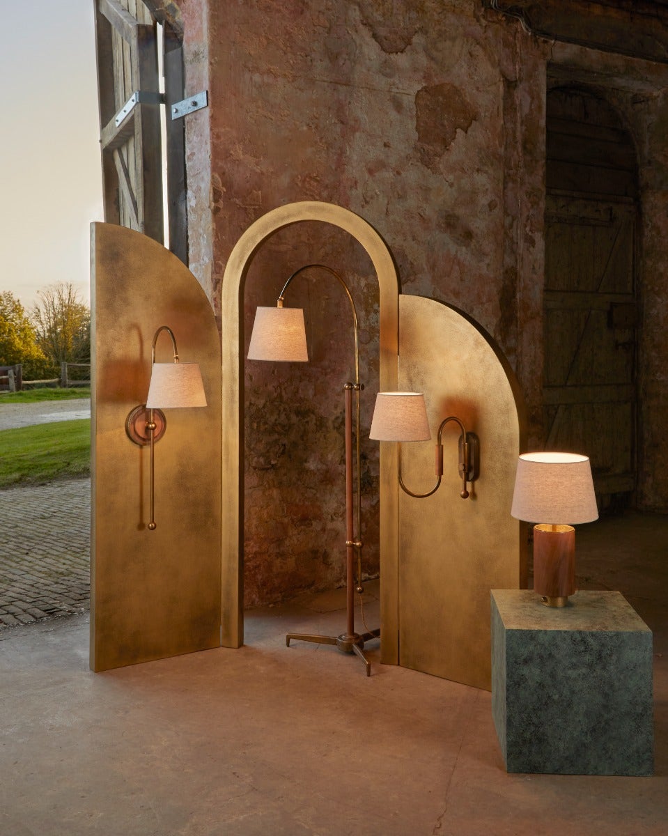 A display of two wall lights, a floor light and table light on brass arch boards in a scenic barn location.